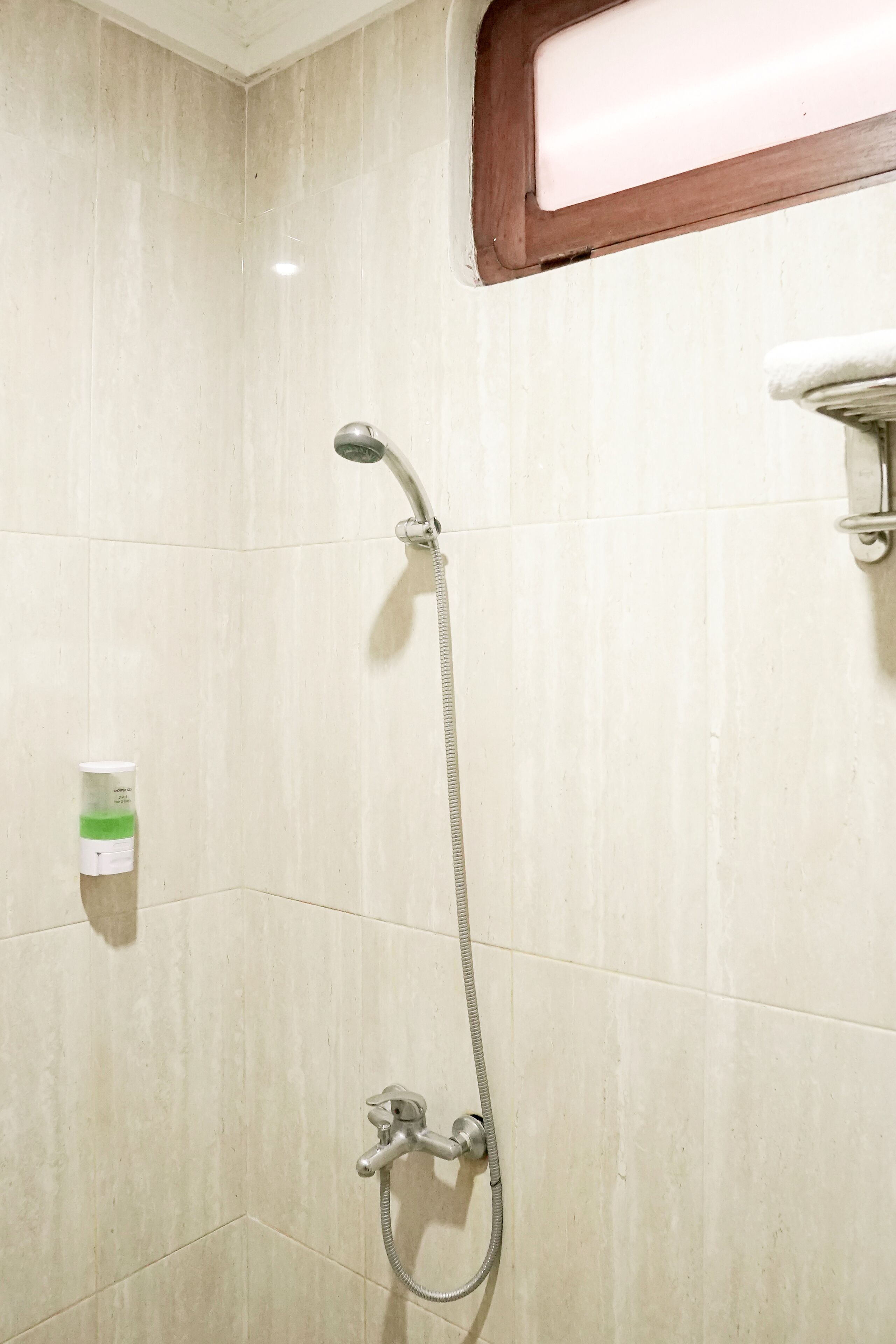 A shower with a handheld showerhead and a wall-mounted faucet.