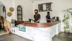 A hotel reception area with a marble counter, a coffee machine, and a menu board. - Airlangga Hotel (Yogyakarta)