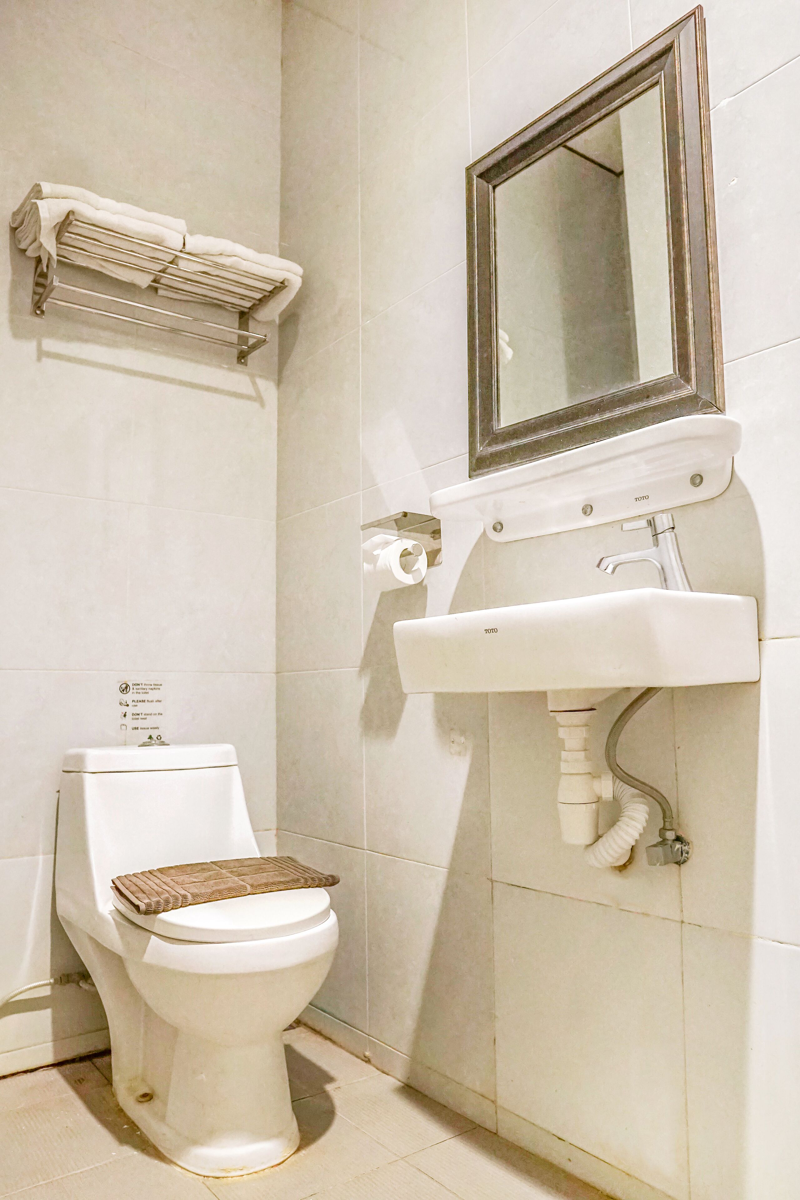 A bathroom with a toilet, a sink, and a mirror.