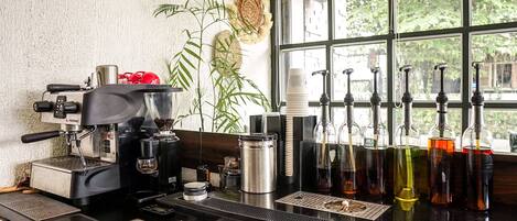 A coffee bar with an espresso machine, coffee cups, and various coffee dispensers.