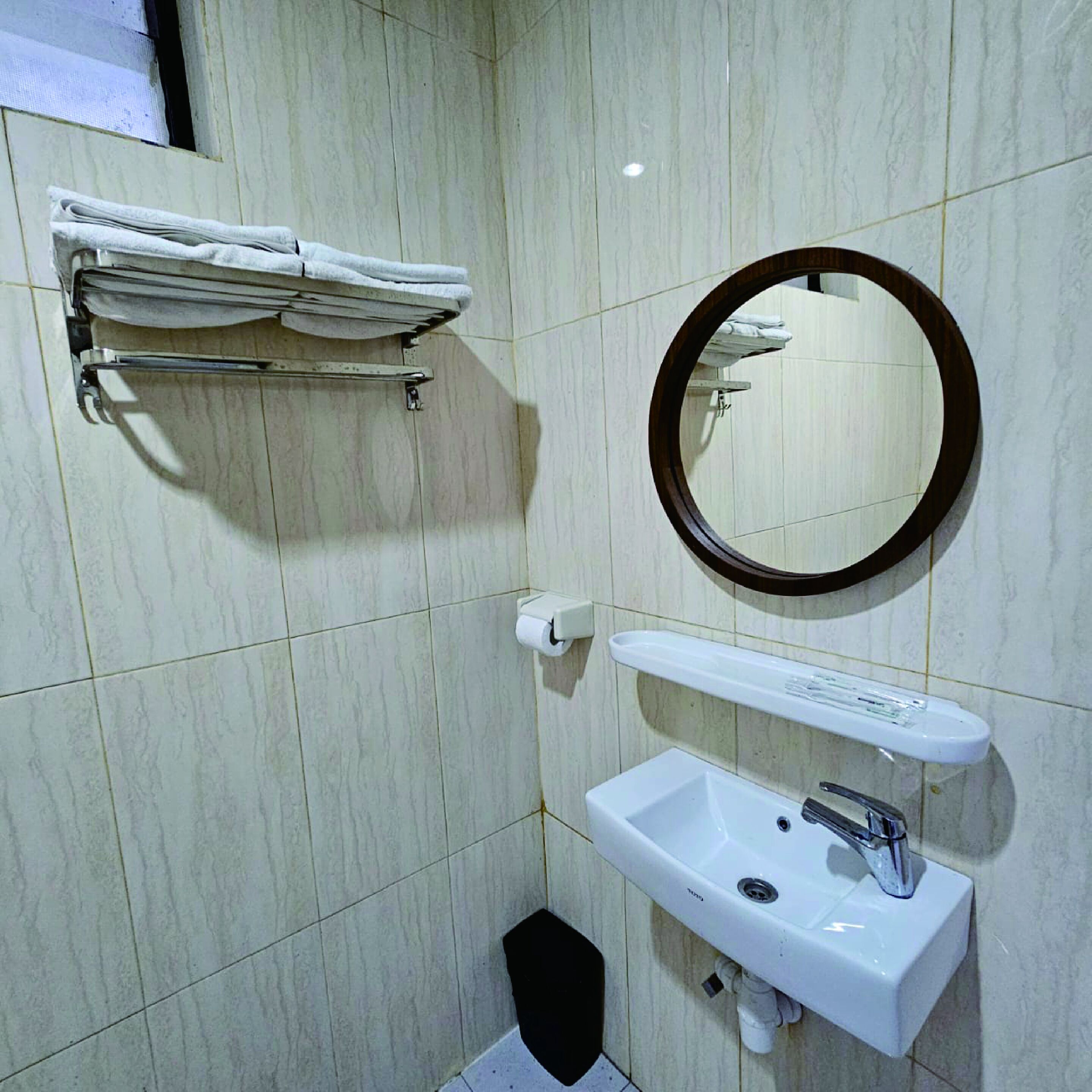 Un bagno con un lavandino bianco, uno specchio e un portascopevoli.