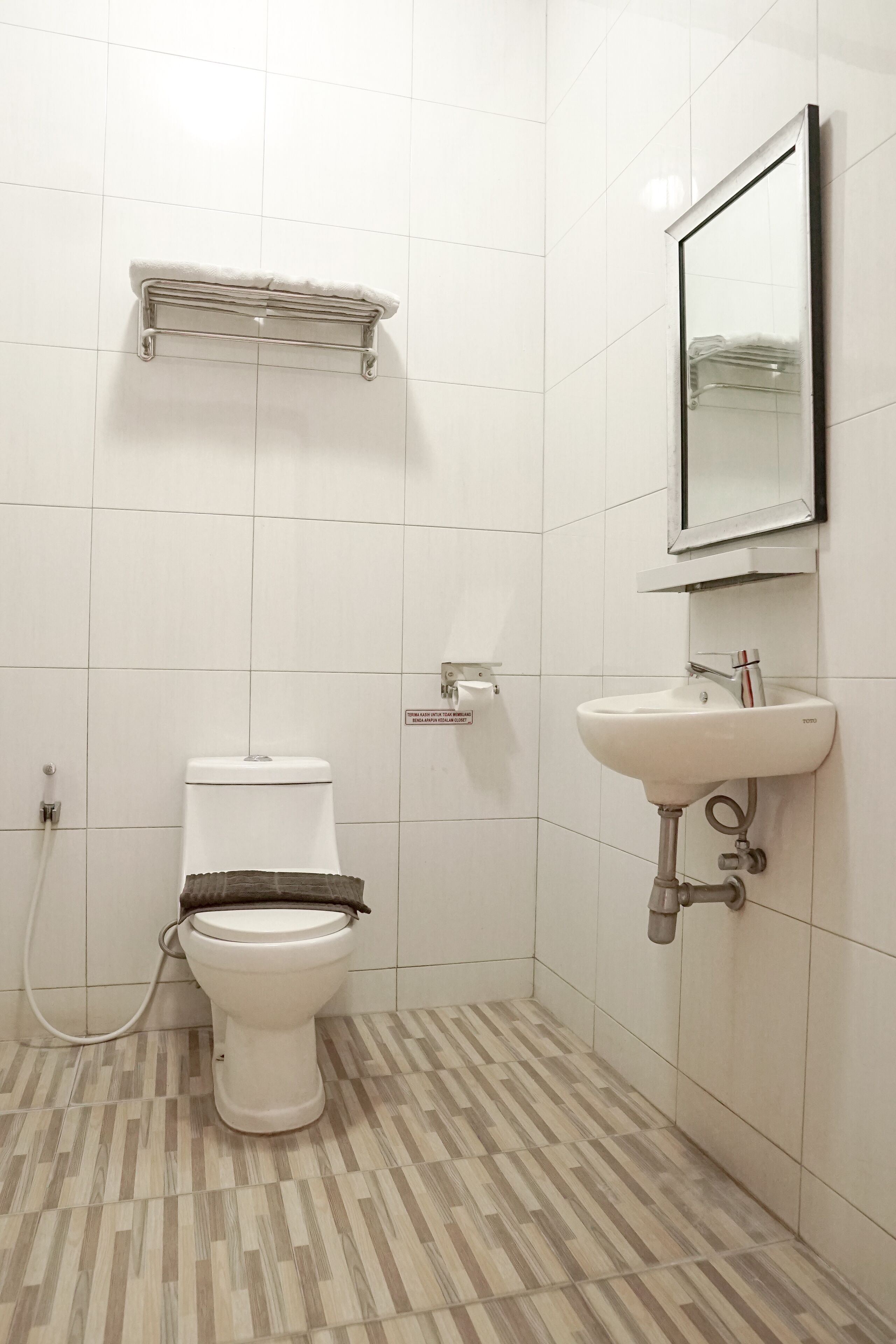 A bathroom with a toilet, sink, and mirror.