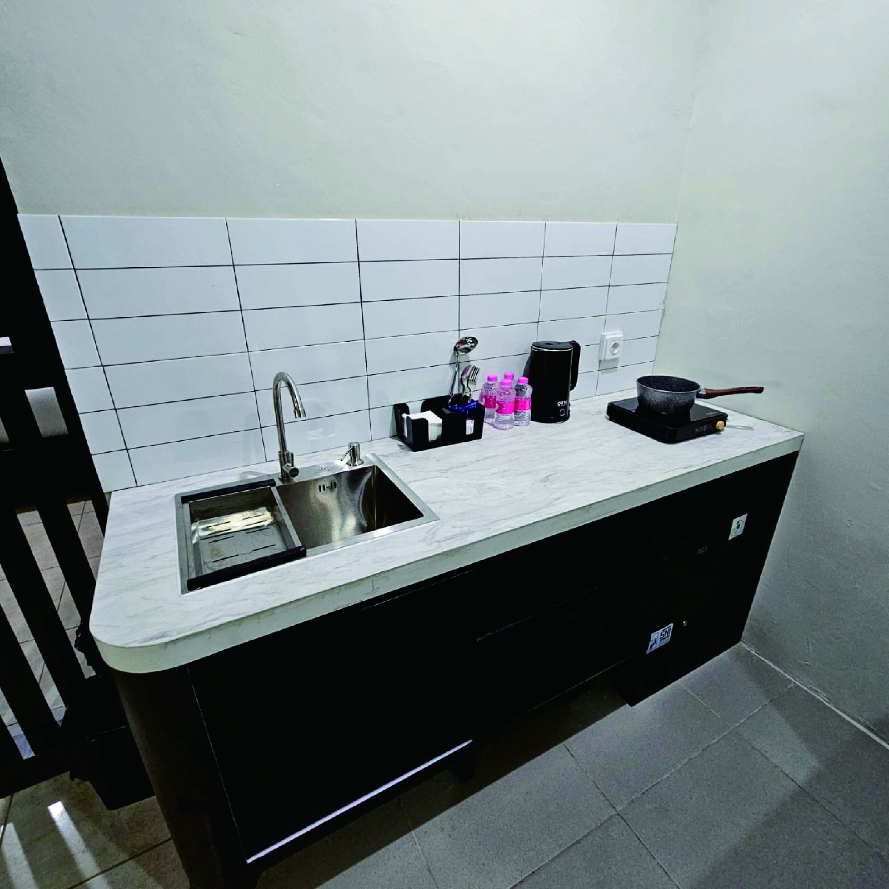 A compact kitchen with a sink, a coffee maker, and a frying pan on the counter.