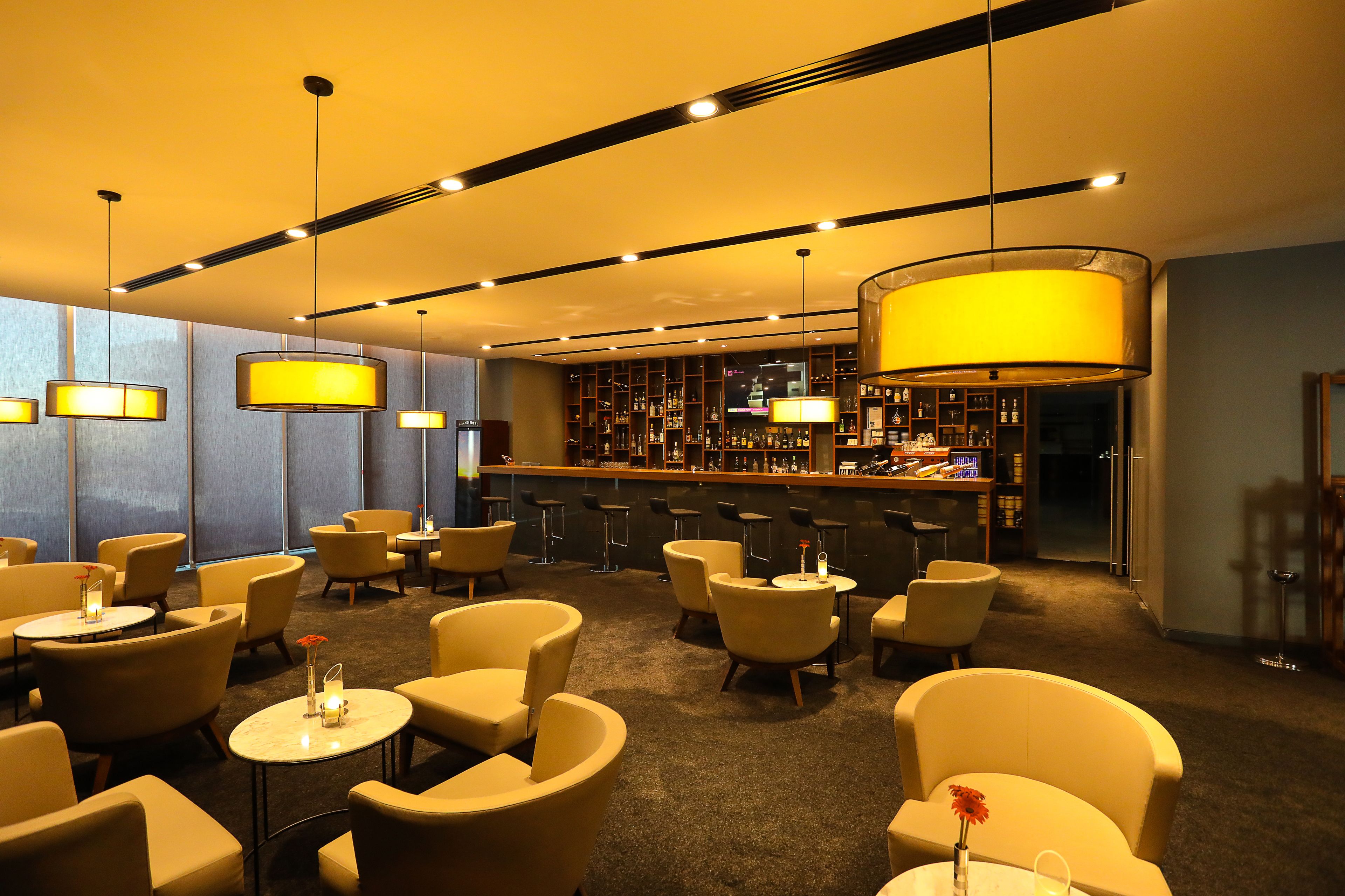 Un hall d’hôtel doté de plusieurs espaces de détente, d’un bar et d’un plafond bien éclairé.