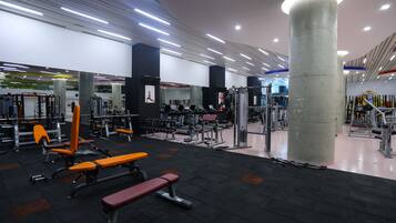 Une salle de sport équipée de divers appareils d’exercice, de bancs et d’une grande colonne.