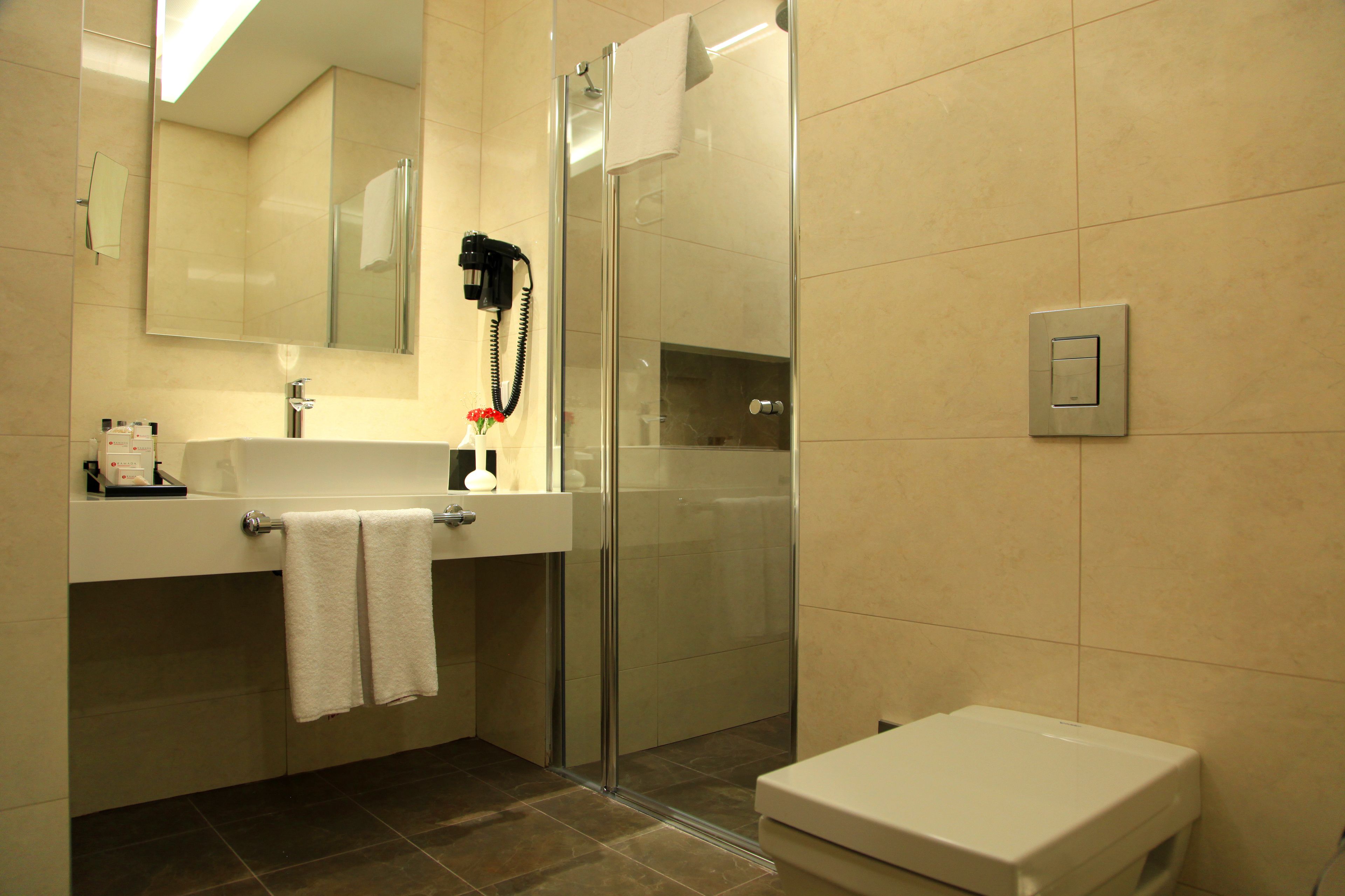 Un baño moderno con cabina de ducha de vidrio, lavabo con toalla y retrete.