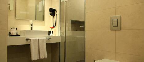 Un baño moderno con cabina de ducha de vidrio, lavabo con toalla y retrete.