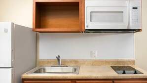 A kitchen with a built-in microwave, a stainless steel sink, and wooden cabinets. - WoodSpring Suites Chesapeake - Norfolk Greenbrier (Chesapeake)