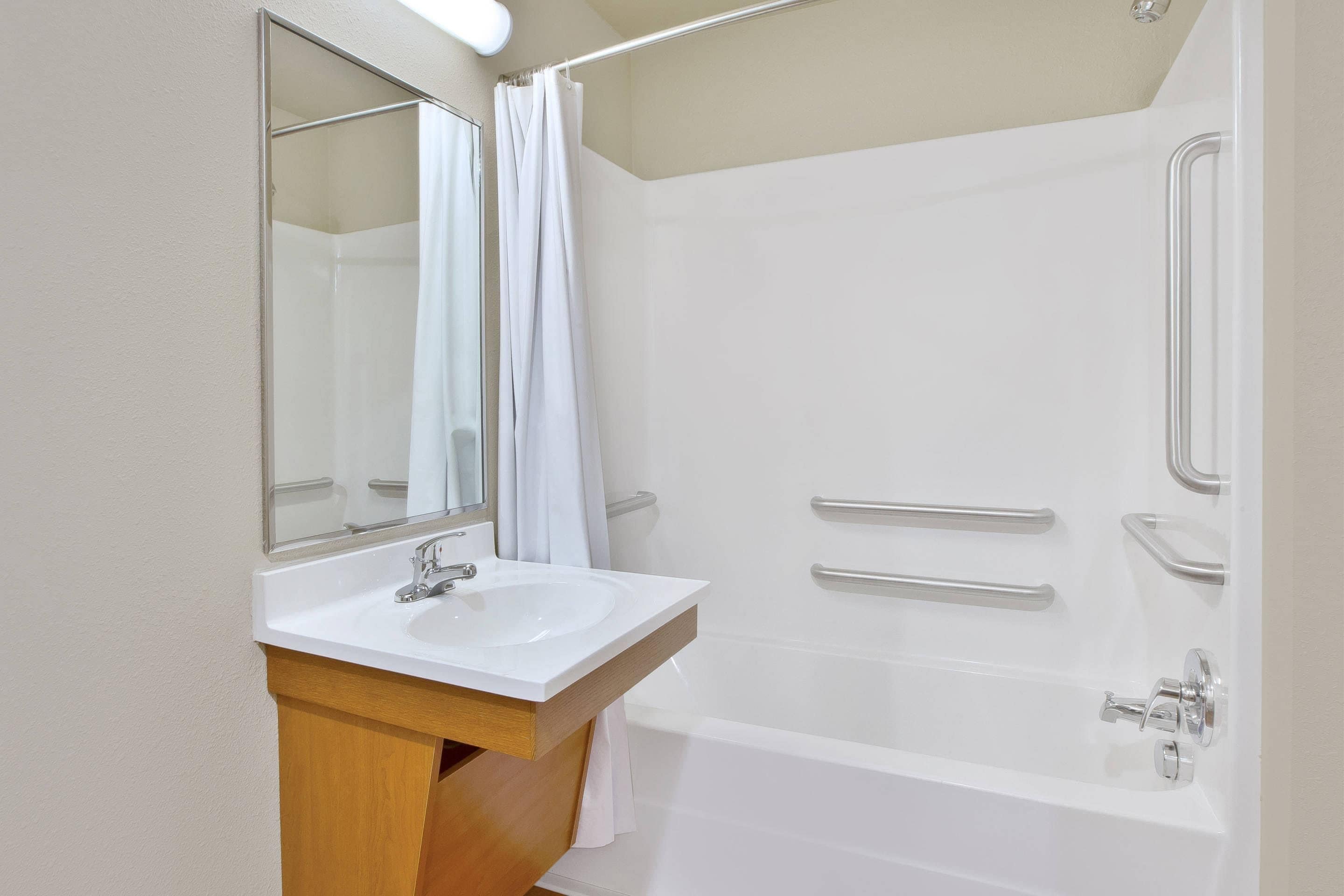 A modern bathroom with a white sink, mirror, and shower.