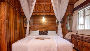 A large bed with white linens, wooden paneling on the walls, and a canopy. - Hotel Troy (Nairobi)