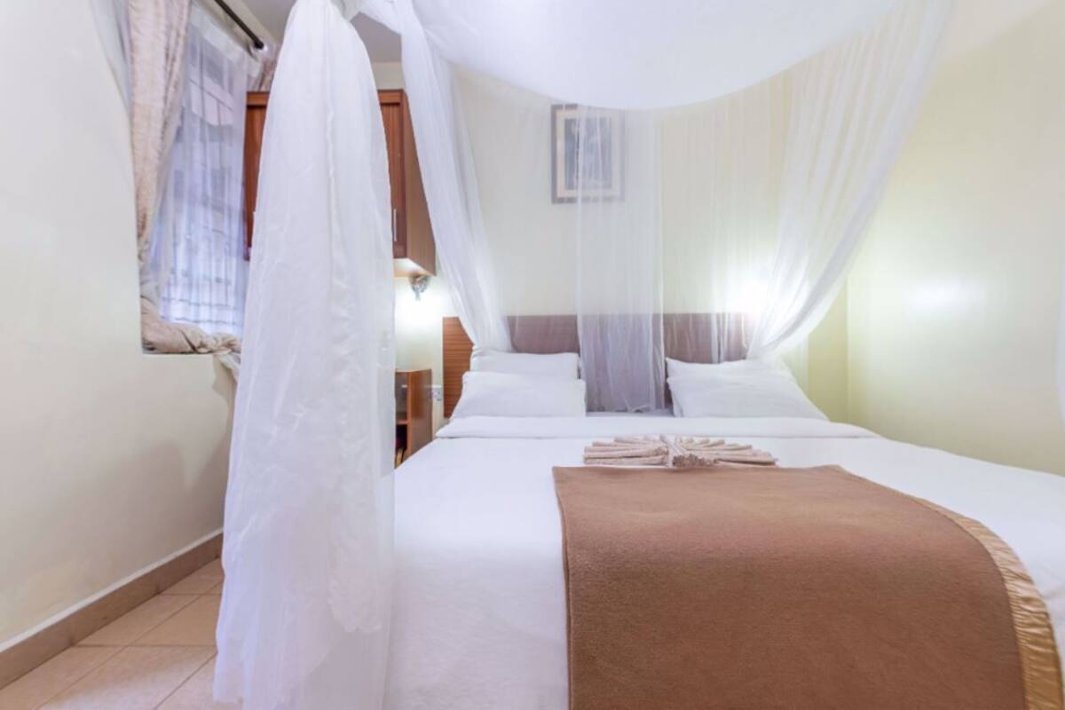 A hotel room with a bed, white curtains, and a mosquito net.