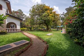 A garden with a brick pathway leading to a white building with a balcony. - Hotel Troy Nairobi (Nairobi)