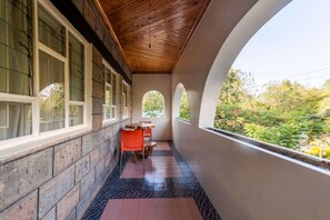 A covered corridor with stone walls, a wooden ceiling, and a view of greenery outside. - Hotel Troy Nairobi (Nairobi)