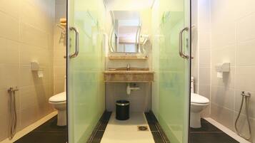 Un baño moderno con dos inodoros, un lavabo, un espejo y una ducha.
