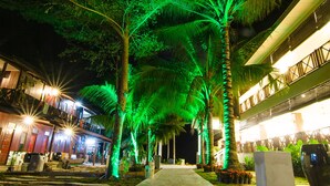 A nighttime walkway lined with palm trees and illuminated by green lights, leading to a building with balconies. - Summer Bay Resort, Lang Tengah Island (Lang Tengah Island)