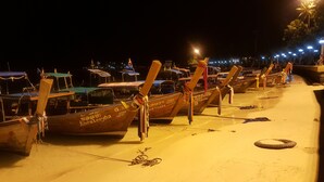 Una hilera de botes tradicionales amarrados a un muelle de noche.