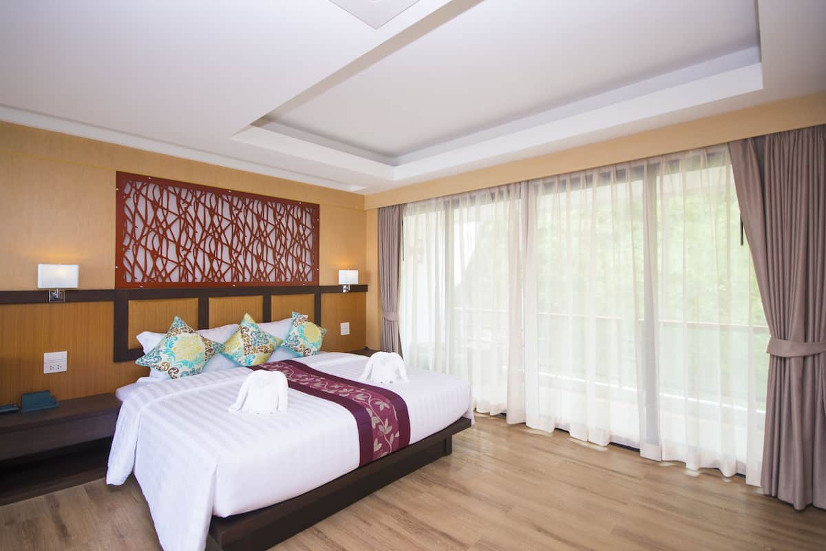 A hotel room with a large bed, wooden headboard, and a decorative wall panel.