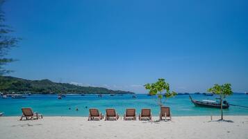 Am Strand, weißer Sandstrand, Liegestühle, Sonnenschirme