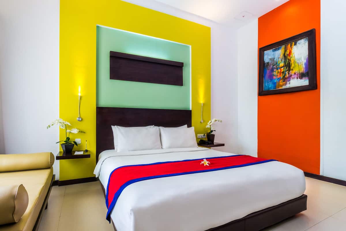 Une chambre d’hôtel moderne, dotée d’un grand lit, de deux tables de chevet et d’une décoration aux couleurs vives.