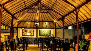 A spacious indoor area with a high, thatched roof structure, multiple seating arrangements, and a bar area with various appliances. - Ozz Hotel - Kuta Bali (Kuta)