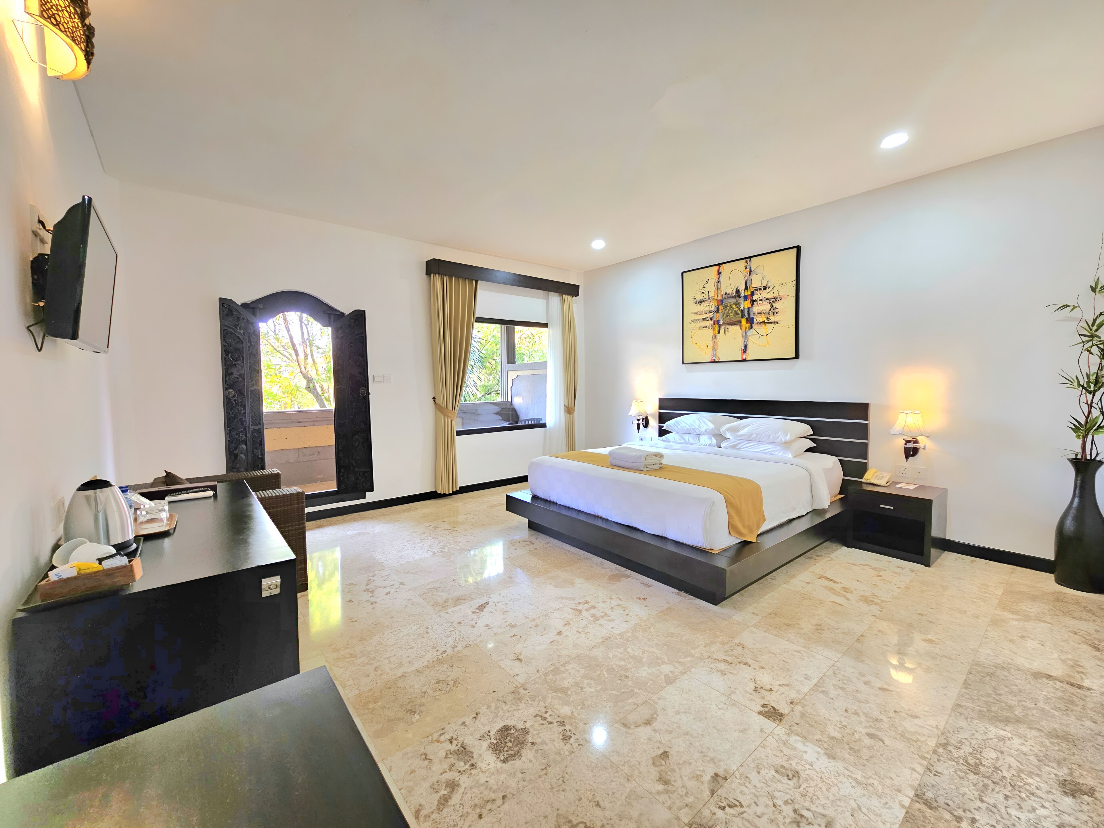 A hotel room with a bed, bedside table, lamp, and a large window with curtains.