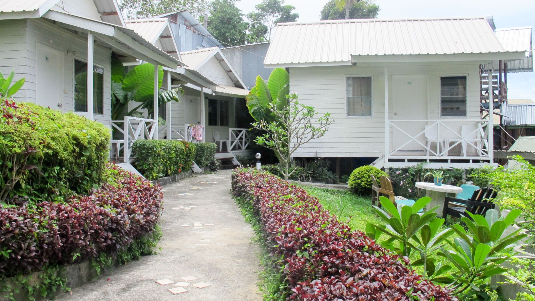 A pathway leading to a row of white buildings with a covered porch area.
