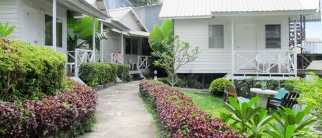 A pathway leading to a row of white buildings with a covered porch area.