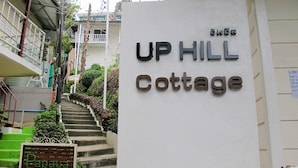 A sign for UP HILL Cottage with a staircase leading up to it.