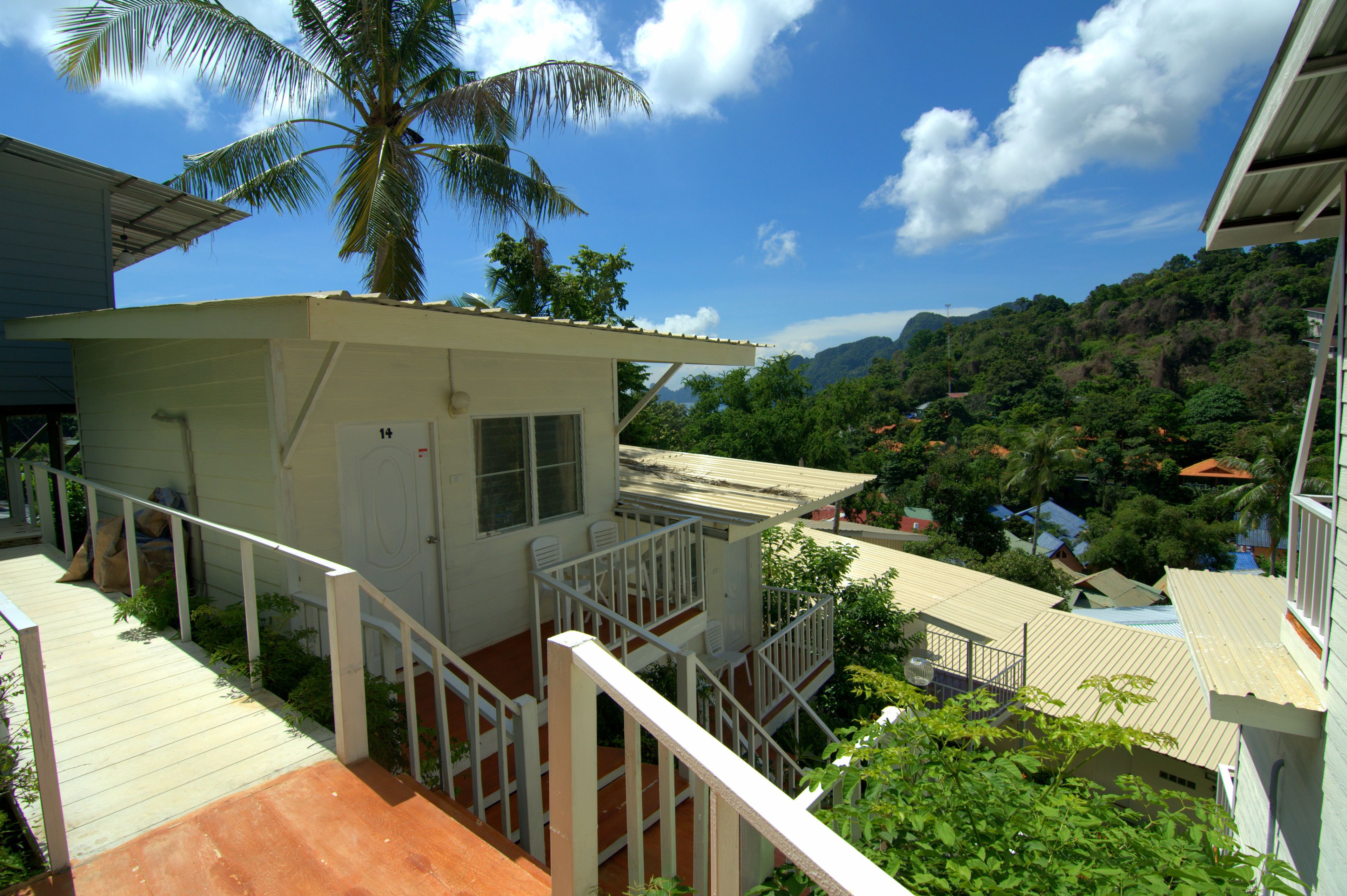 A small, single-story building with a balcony and a view of a mountainous landscape.