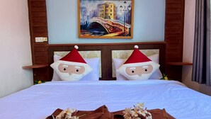 Habitación de hotel con una cama, dos almohadas con caras de Santa, un cuadro de un puente y una toalla marrón con motivos florales.