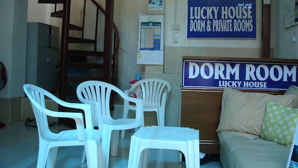 A room with a bed, a sofa, and a sign indicating 'Lucky House Dorm & Private Rooms'. - Lucky House Dorm Room - Hostel (Ko Phi Phi)