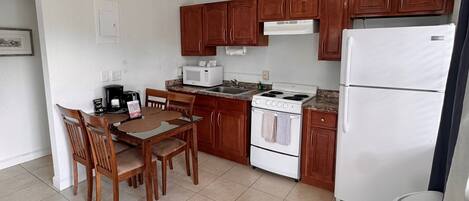 A compact kitchen with wooden cabinets, a white stove, a microwave, and a refrigerator.