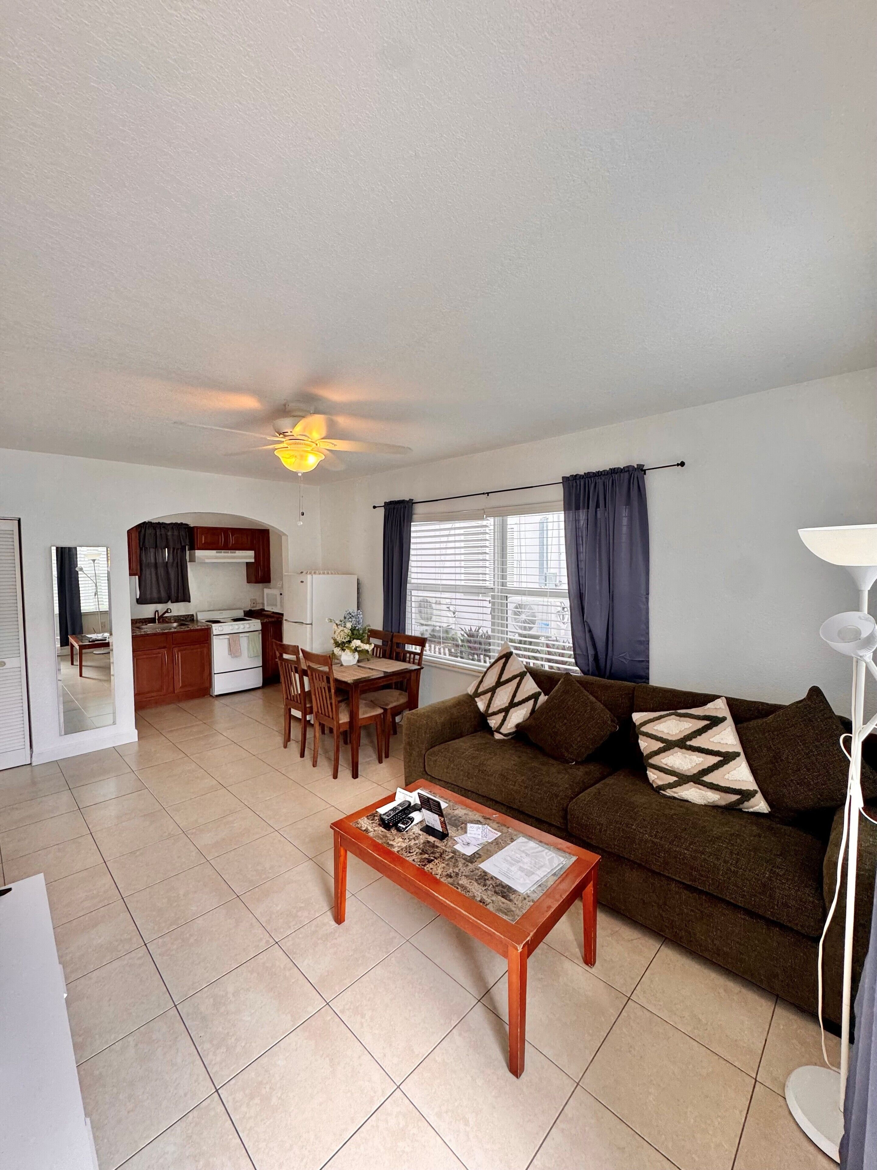 A living room with a sofa, coffee table, and a dining area with chairs and a table.