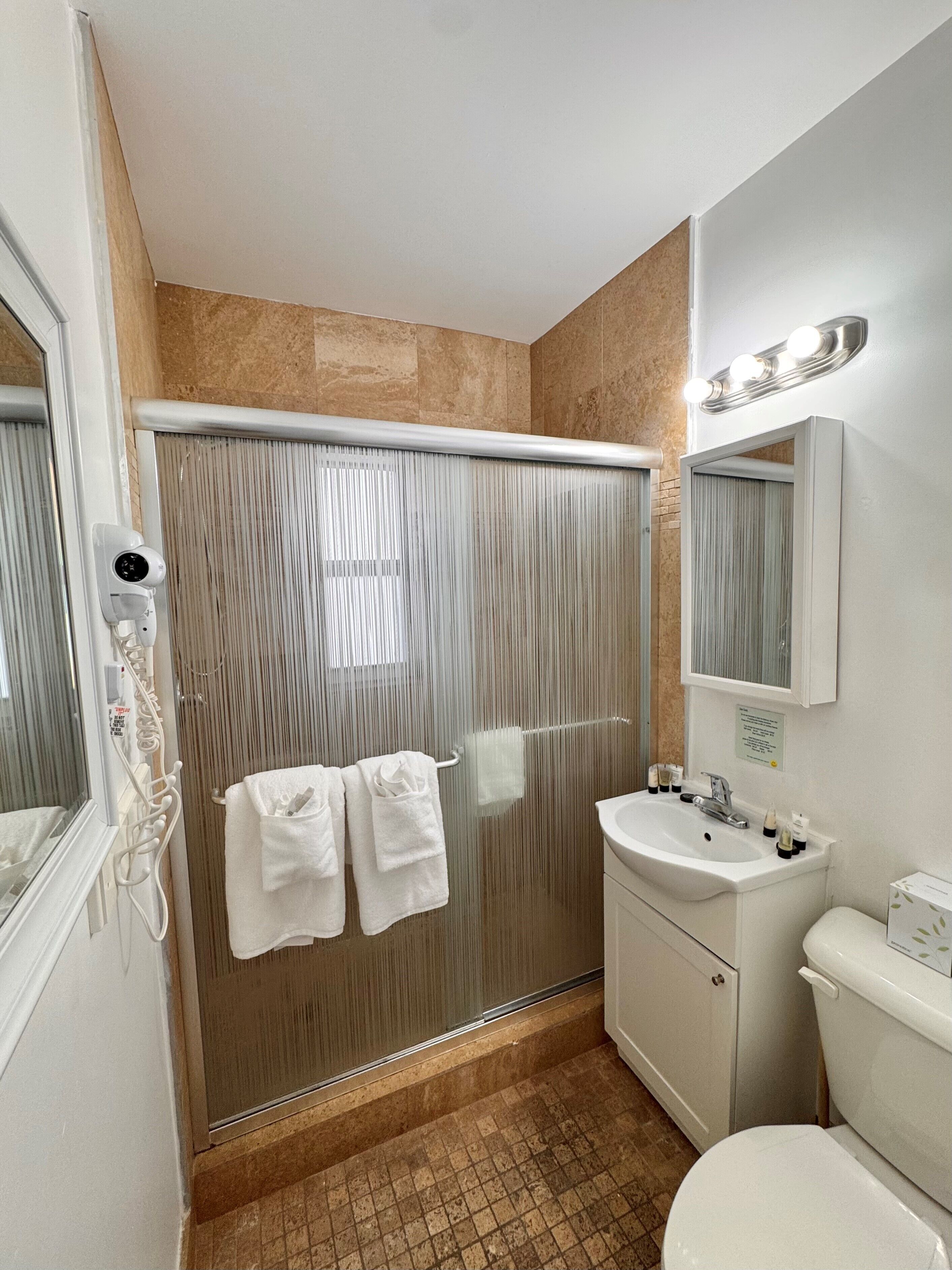 A bathroom with a shower, a sink, a toilet, and a mirror.