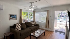 A living room with a sofa, coffee table, and ceiling fan. - Coral Key Inn (Lauderdale-by-the-Sea)