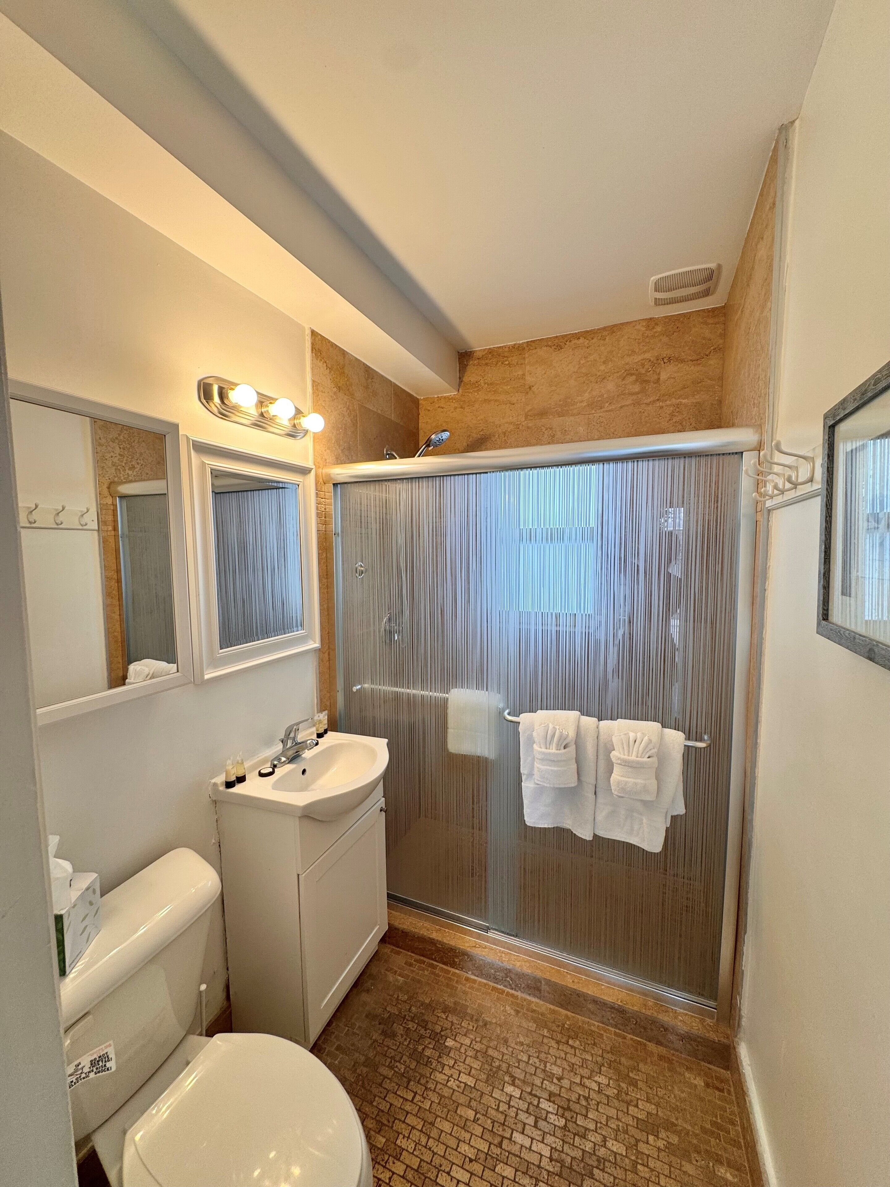 A modern bathroom with a shower, toilet, sink, and vanity.