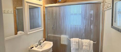 A modern bathroom with a shower, toilet, sink, and vanity.