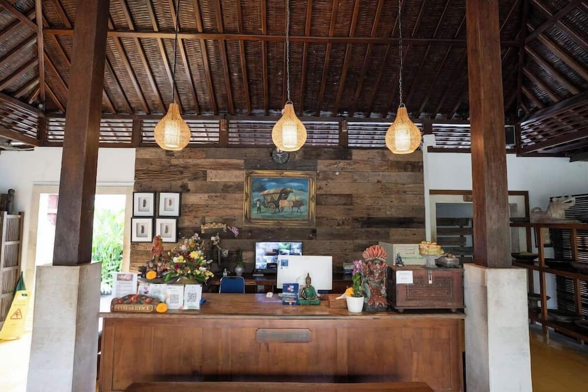 A reception area with wooden beams, hanging light fixtures, a painting, and a desk with various items.