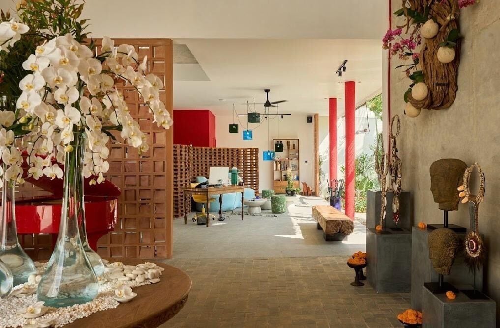 A spacious living area with a wooden partition, a red piano, and a variety of decorative items including a vase with white flowers.