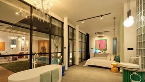 A modern hotel room with a large glass wall, a bathtub, a bed, a small pool, and a dining area visible through the glass. - HOTEL EDEN UBUD (Ubud)