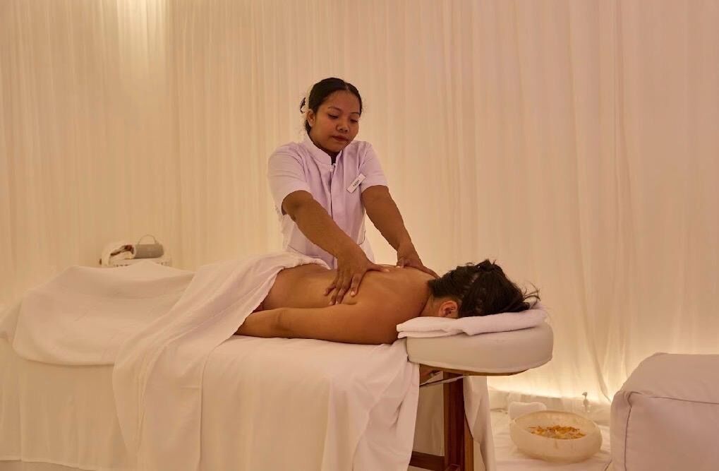 Une séance de massage dans une pièce équipée d’une table de massage, d’une serviette et d’un récipient contenant ce qui semble être de l’huile de massage.