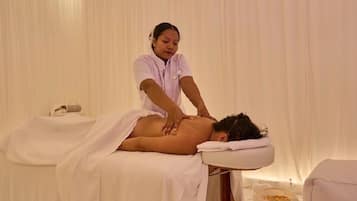 Une séance de massage dans une pièce équipée d’une table de massage, d’une serviette et d’un récipient contenant ce qui semble être de l’huile de massage.