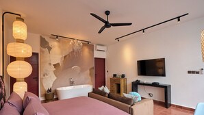 A modern bedroom with a large bed, a bathtub, a desk, and a television. - HOTEL EDEN UBUD (Ubud)