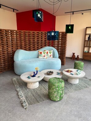 A modern living room with a blue sofa, round coffee tables, and a wooden wall. - HOTEL EDEN UBUD (Ubud)