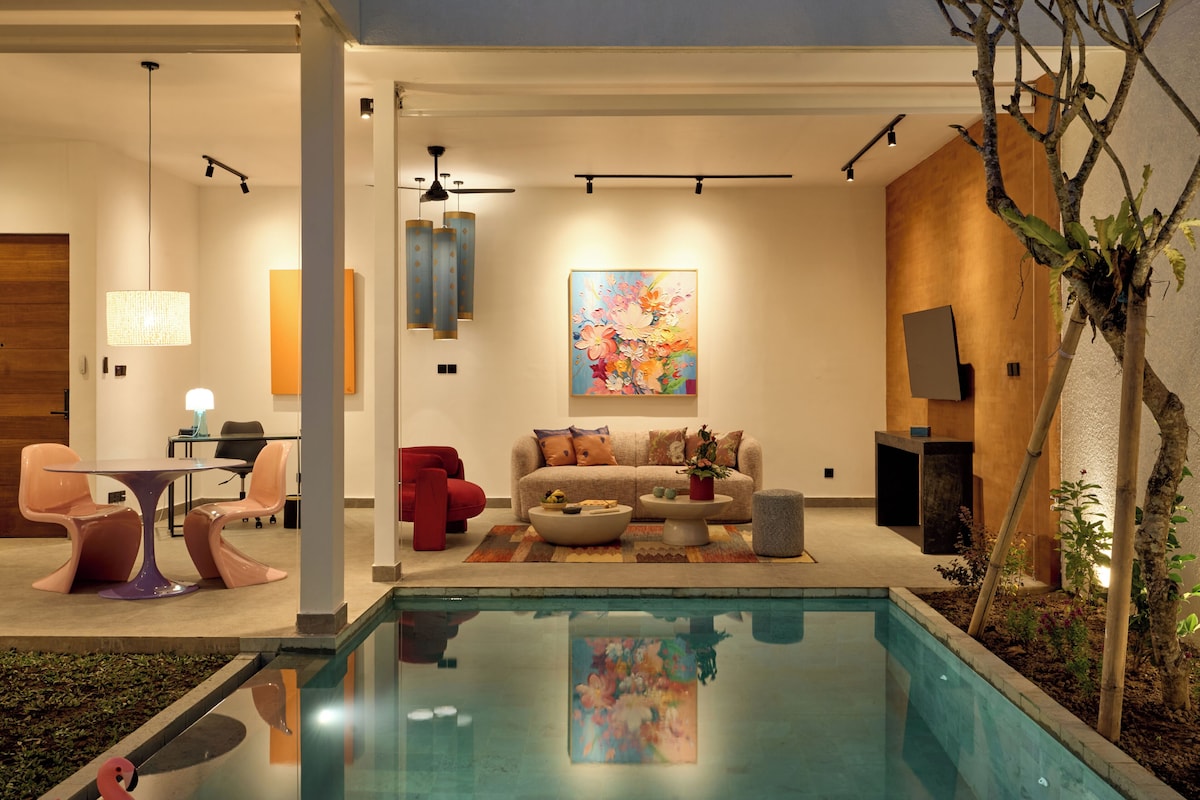 A modern interior with a pool, a sofa set, a dining table, and a large painting.