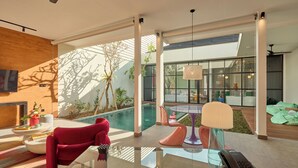 A modern living room with a glass table, red sofa, and a pool view. - HOTEL EDEN UBUD (Ubud)
