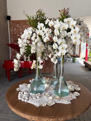 A round wooden table with a floral centerpiece, surrounded by white pebbles. - HOTEL EDEN UBUD (Ubud)