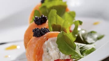 Un plato con un alimento que incluye salmón, verduras de hoja y una rodaja de fruta roja.