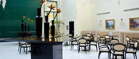 A spacious lobby with a central bar area, multiple seating arrangements, and decorative vases with flowers.