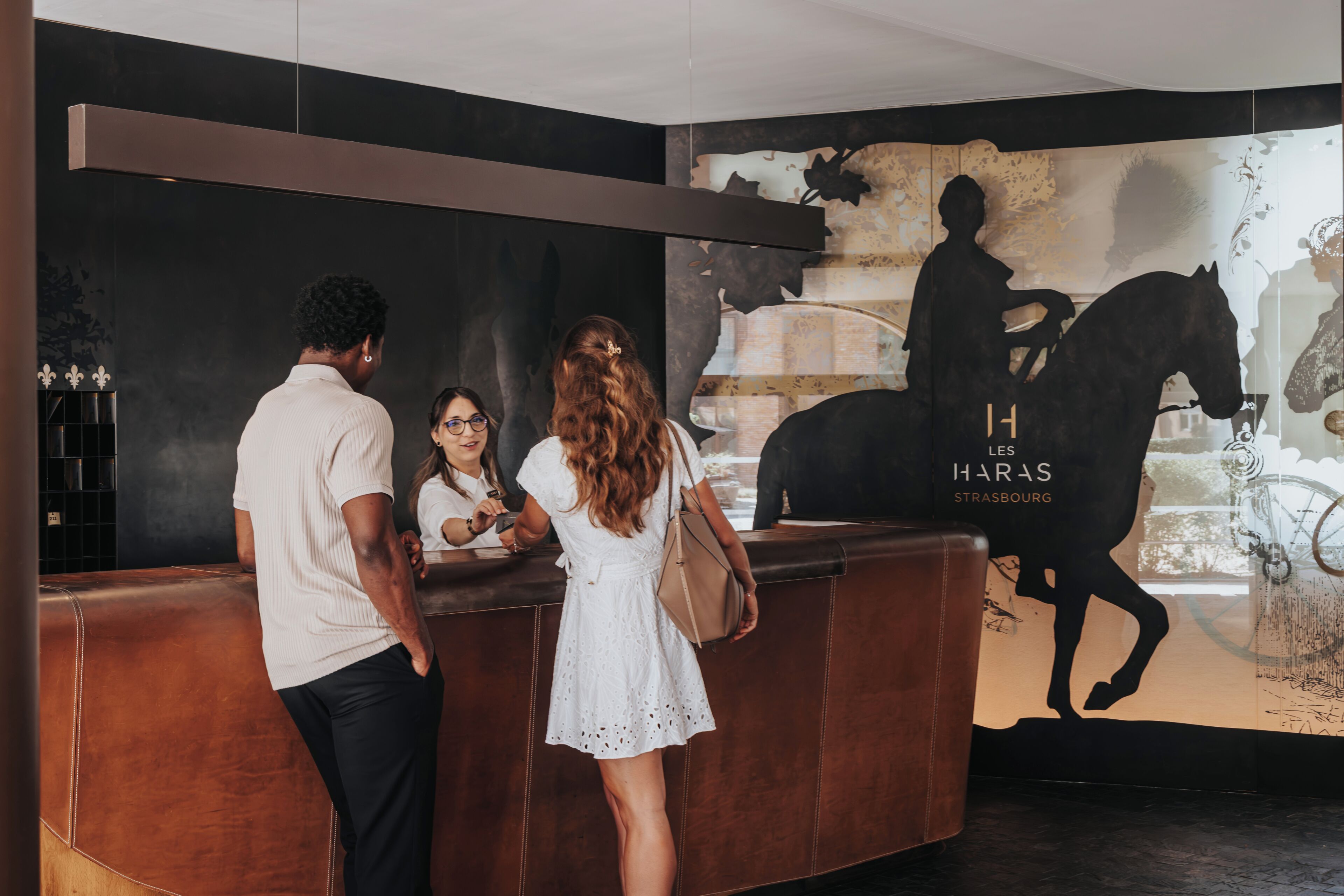 A reception area with a modern design, featuring a reception desk and a large wall mural with a horse silhouette.
